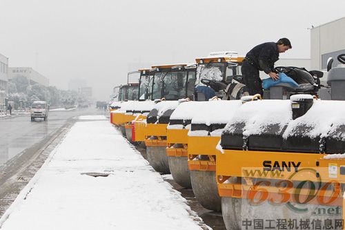 寒風中，工人細心地除去壓路機上的積雪